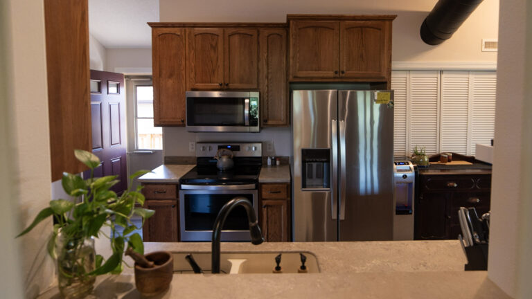 An image of the fully-equipped kitchen at River Bend Vacation Home. The image shows the stainless steel refrigerator sink, oven and microwave.